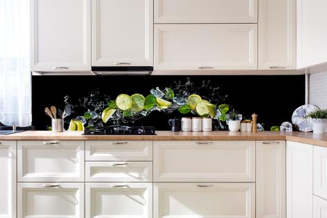 Küchenrückwand mit Zitronen und Limetten vor schwarzem Hintergrund